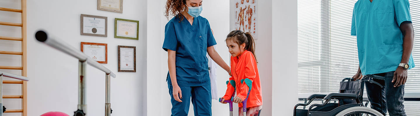 Child standing out of wheelchair with physical therapy
