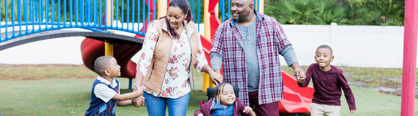 Family of five holding hands while walking through a park