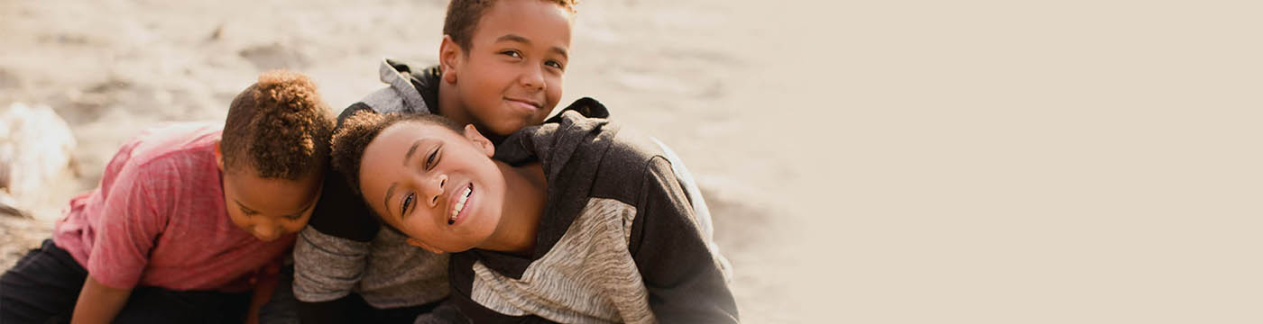 Three boys cuddling on beach