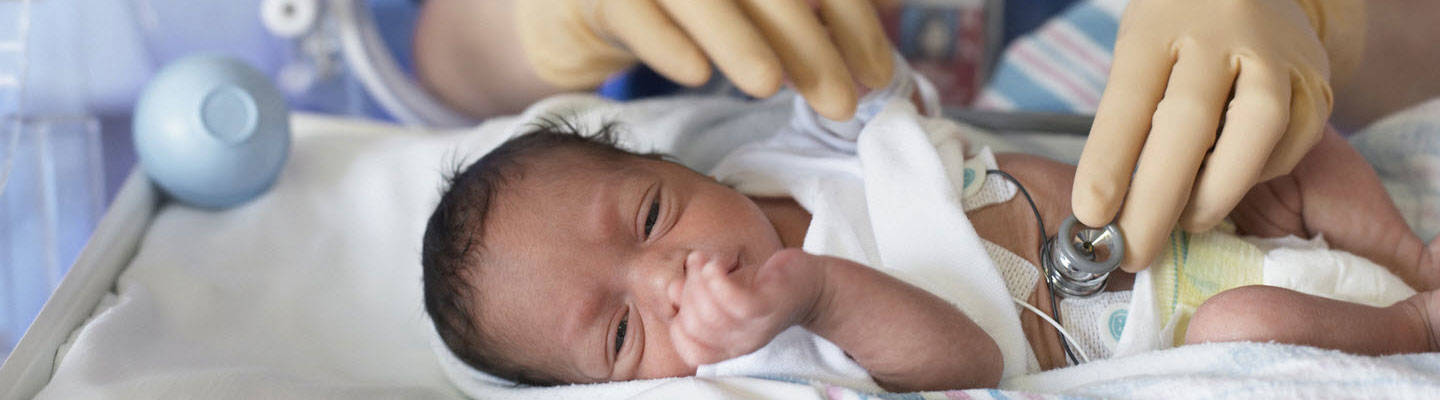 A newborn being examined in incubator