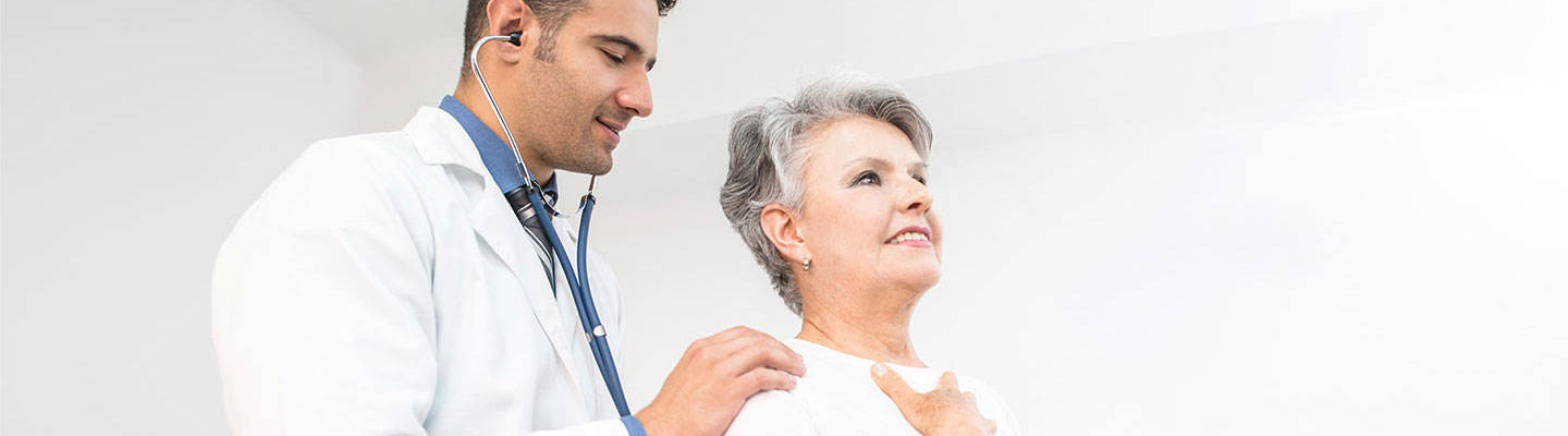Male doctor examining senior woman with a stethoscope
