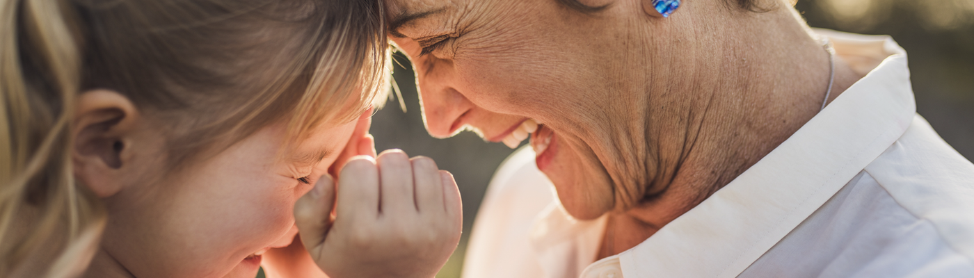 Close up photo of a grandmother and her granddaughter smiling