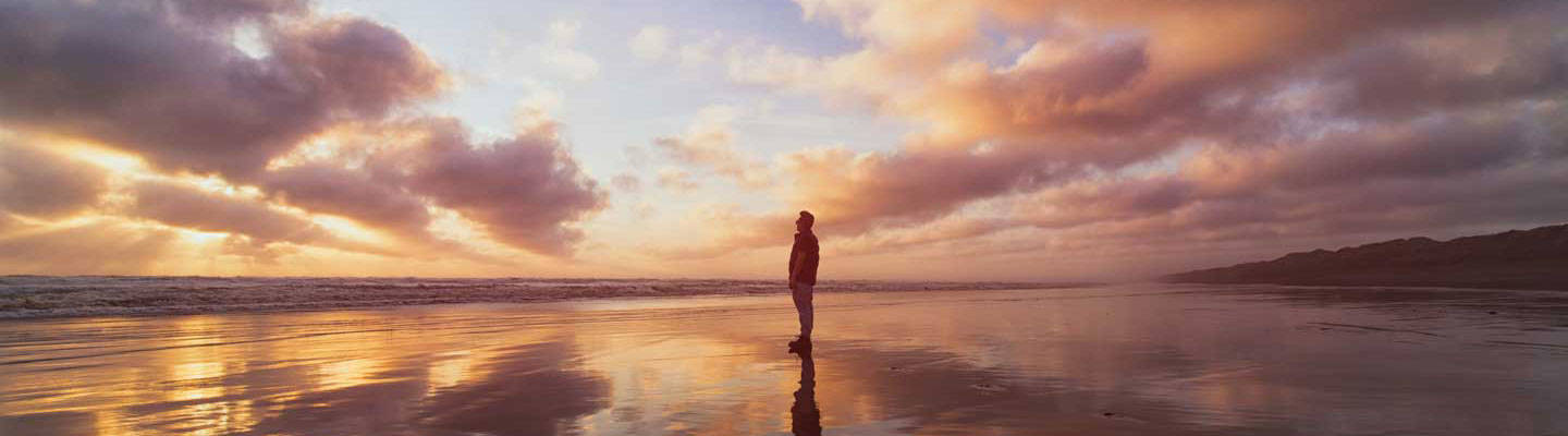 Man standing on sandy beach during sunset