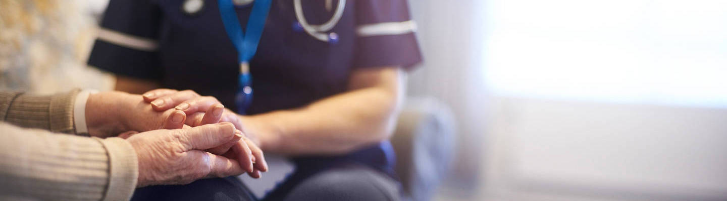 Nurse comforting patient and holding her hands