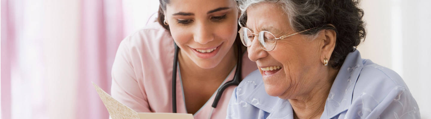 Caregiver reading to a happy senior woman