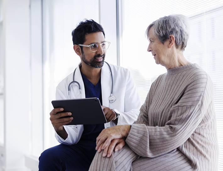 doctor reviews information on tablet with senior patient
