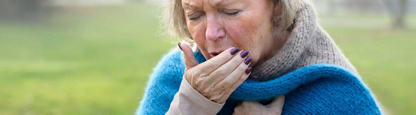 Older woman coughing into hand