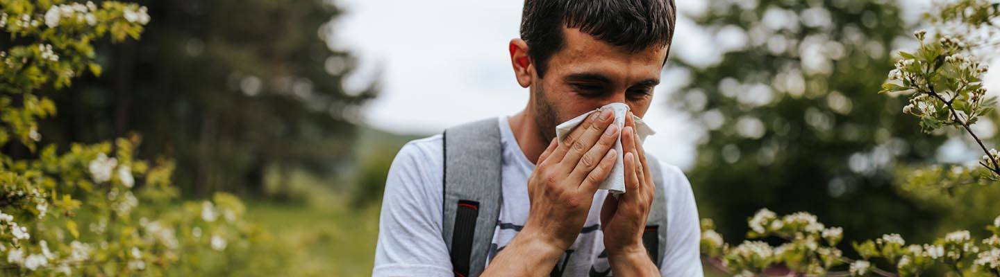 Man with pollen allergy sneezing in field