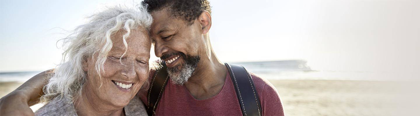 Mature woman and man embracing on beach