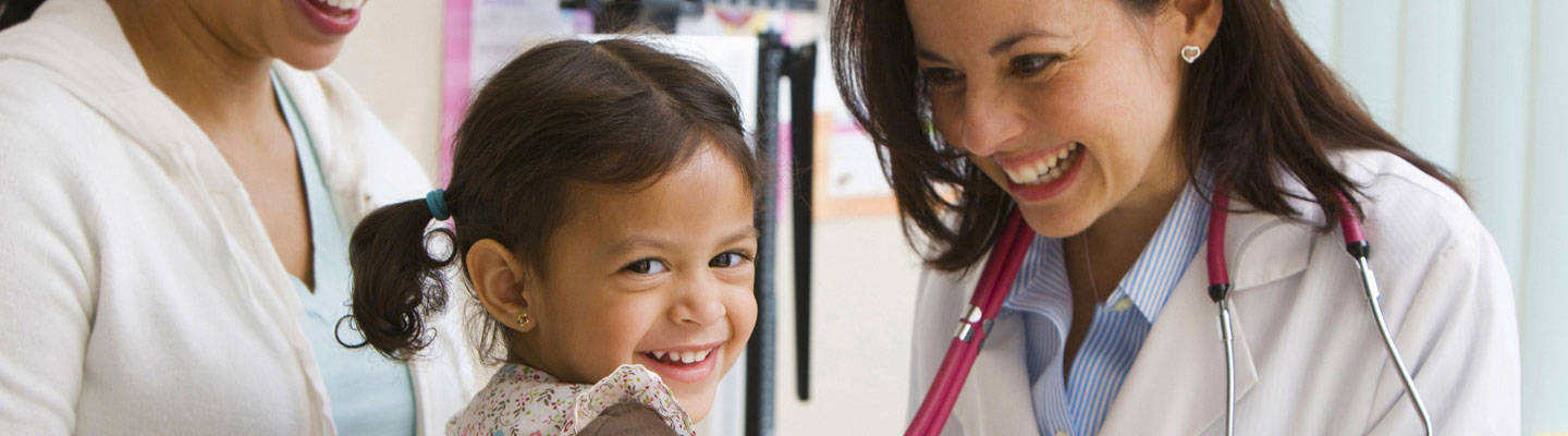 A pediatrician examines a young girl in a clinic.