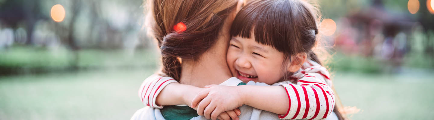 Young girl smiling while mother carries her